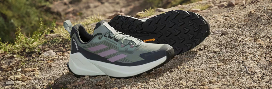 Adidas Terrex Trail running shoes on rocky terrain, featuring prominent tread and grey with purple accent design