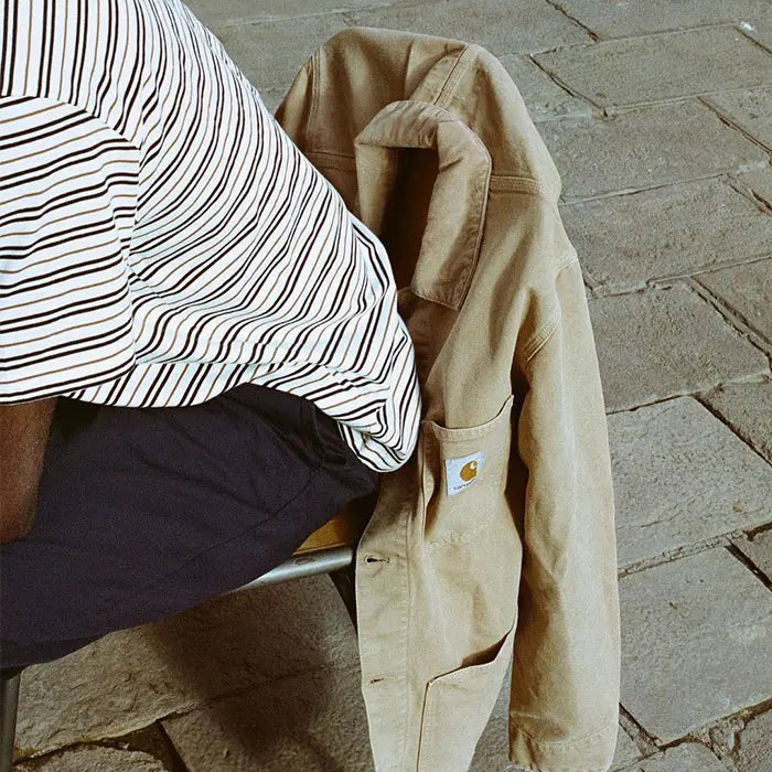 Person wearing Carhartt WIP navy trousers, striped shirt and Carhartt WIP jacket