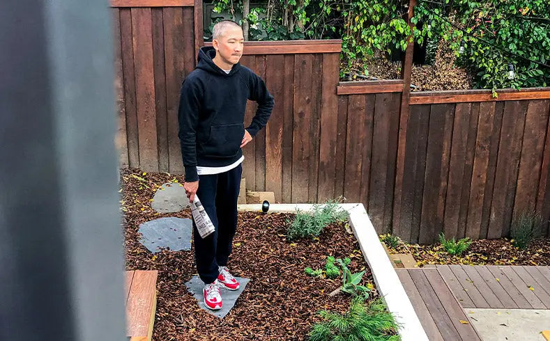 Jason Markk holding a newspaper standing in his Garden