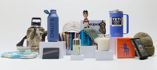 Selection of lifestyle accessories including YETI Rambler mug, Chilly’s bottle, Carhartt bag, fragrance, wallet, beanie and candle.