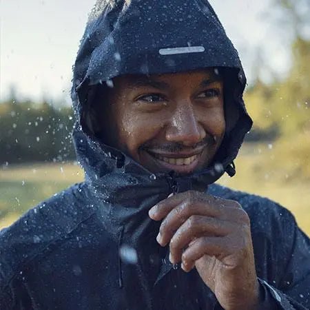 Smiling man in a waterproof Fjallraven jacket with a hood.