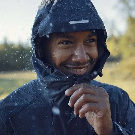 Smiling man in a waterproof Fjallraven jacket with a hood.