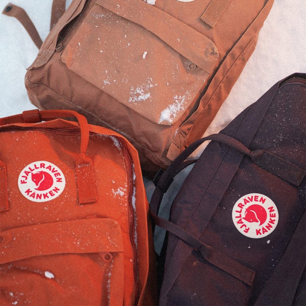 Person sitting on a rock with a red Fjällräven Kånken backpack.