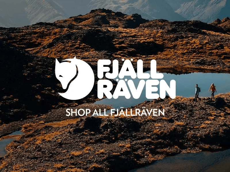 Two hikers exploring a rugged mountain landscape with a clear blue sky, over a promotional banner for Fjällräven with the brand's logo and the call to action 'Shop all Fjällräven'.
