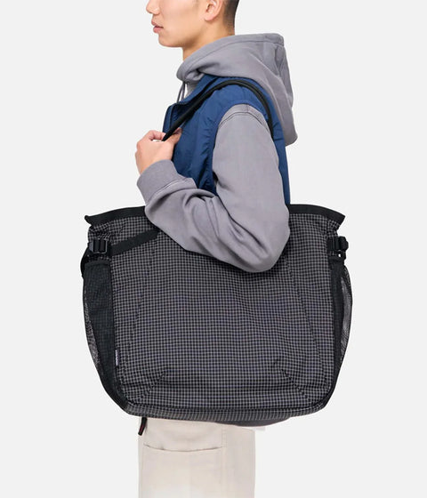 Person carrying a black checkered bag on a white background