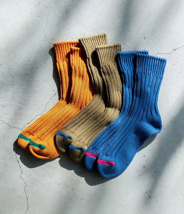 Three pairs of socks in orange, brown, and blue on a textured surface